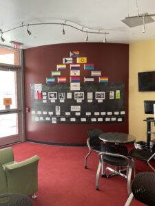 A Pride month display with various pride flags on a wall in the teen area.