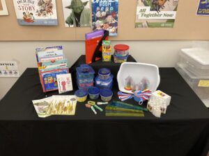 The contents of the "Measure On" trunk are displayed on a table. To see the list of items included you may visit the booking page.