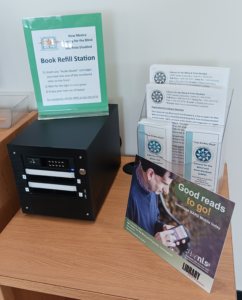 Book Refill station on a desk with Library for the Blind and Print Disabled promotional material to the right of it.