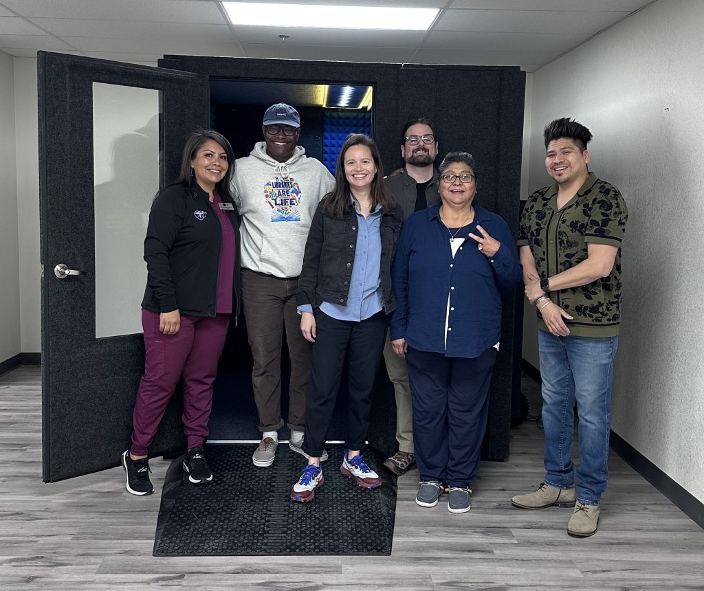 Six people standing in front of a WhisperBooth at the Mescalero Public Libary in Mescalero, New Mexico